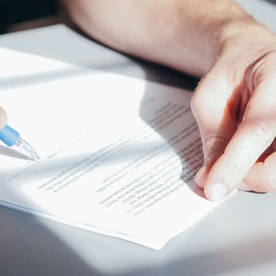 Close-up of a hand signing a printed agreement