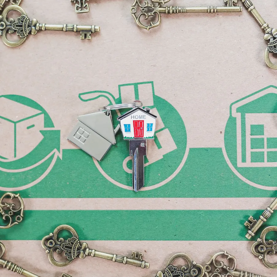A small house-shaped key ring lying among old keys