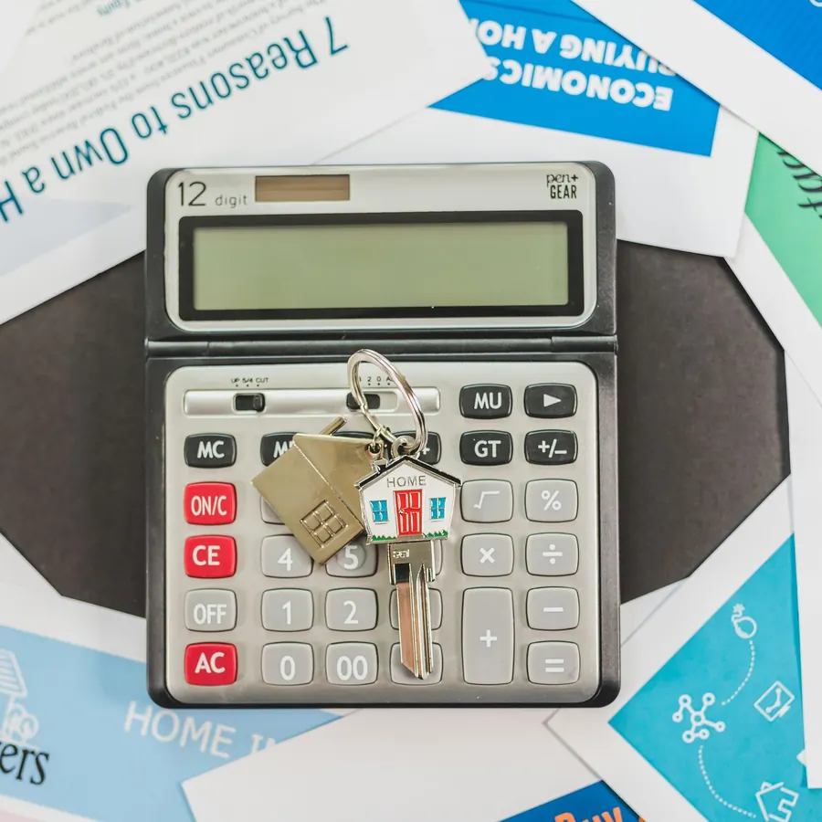 A calculator and house keys on top of home buying leaflets